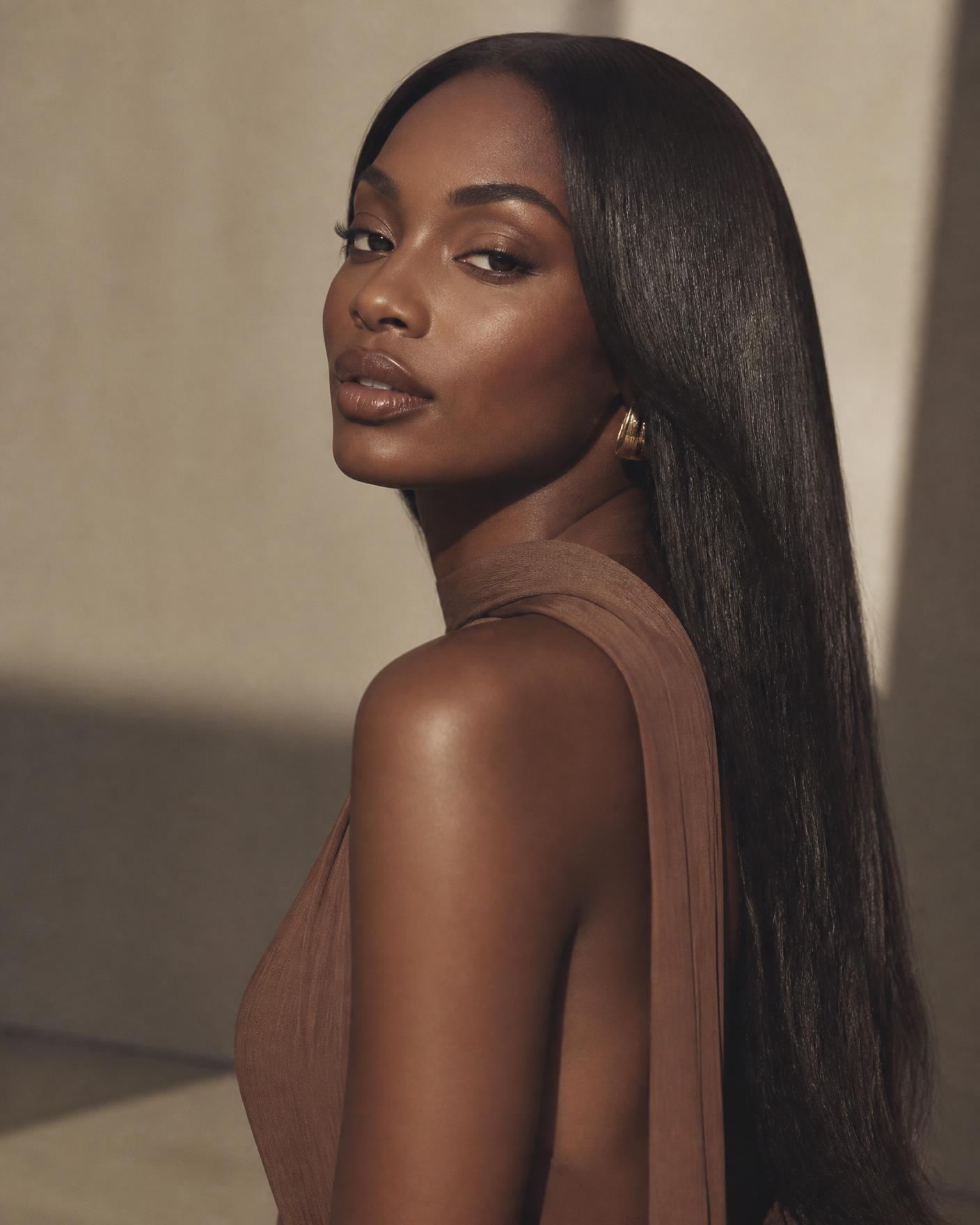 Model wearing a sleek, glossy Nekky Hairs straight wig in warm studio light